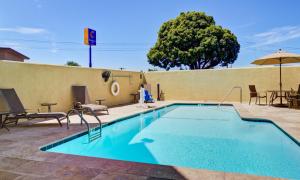 a swimming pool with chairs and a table and an umbrella at Comfort Inn Sunnyvale - Silicon Valley in Sunnyvale