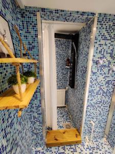 a bathroom with a blue tiled shower with a mirror at Polku Apartaments in Imatra