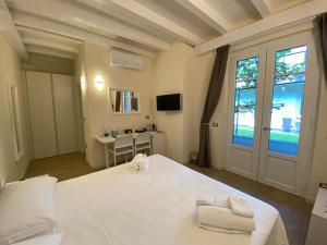 Un dormitorio con una gran cama blanca y una ventana en Garden Lodge, en Stresa