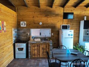 a kitchen with a table and a stove and refrigerator at Las Mozitas 1 in Barra del Chuy