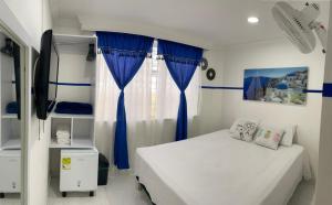 a bedroom with a bed and a window with blue curtains at Casa Hotel Manco Mora in Medellín