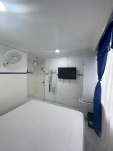 a bedroom with a white bed and a tv at Casa Hotel Manco Mora in Medellín