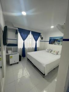 1 dormitorio con 1 cama grande y cortinas azules en Casa Hotel Manco Mora en Medellín