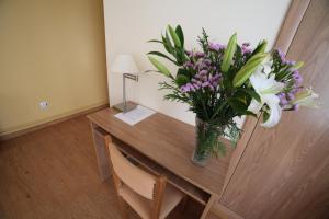 un vase de fleurs sur un bureau dans la chambre dans l'établissement Hotel Río Ulla Monterroso, à Monterroso