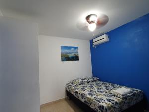 a blue bedroom with a bed and a ceiling fan at Hostal Villa Mayte Coronado in Las Lajas