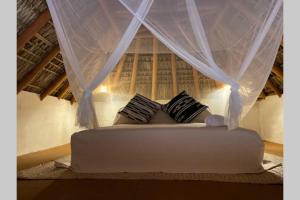 a bed in a room with a curtain and pillows at Casa Coconut in Puerto Escondido