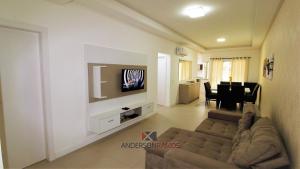 a living room with a couch and a tv on a wall at 1068 - Apartamento com vista para o mar in Bombinhas