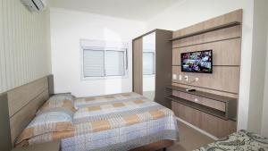 1 dormitorio con 1 cama y TV. en 1069 - Praia de Bombinhas locação de temporada, en Bombinhas