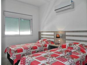2 camas en un dormitorio con mantas rojas y blancas en 1058 - Praia de Bombinhas locação de temporada, en Bombinhas