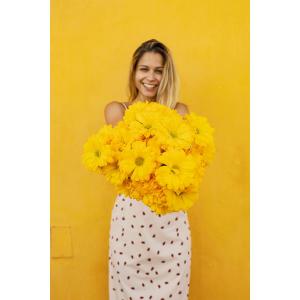 a woman holding a bunch of yellow flowers at CASA AMARELA in Avis