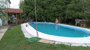 uma mulher sentada ao lado de uma piscina em Kuca na selu sa bazenom em Štitar