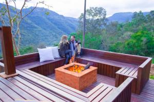 a man and woman sitting on a deck with a fire pit at Valle Ristretto in Gramado