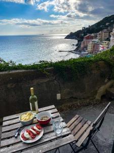 a picnic table with food and a bottle of wine and the ocean at La Casa di Milly in Sori
