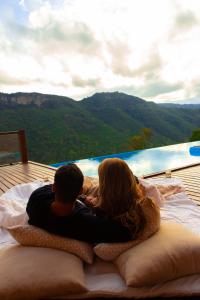 un hombre y una mujer sentados en una cama frente a una ventana en Valle Ristretto, en Gramado