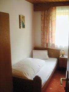 Bett in einem kleinen Zimmer mit Fenster in der Unterkunft Haus Alpenblick in Pertisau