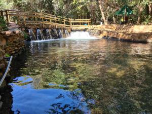 eine Brücke über einen Teich mit einem Wasserfall in der Unterkunft Apto 345 Thermas Paradise in Rio Quente
