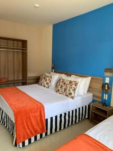 um quarto com 2 camas e uma parede azul em Ondas Praia Resort Apartamento em Porto Seguro