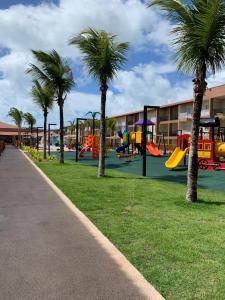 a park with a playground with palm trees and slides at Ondas Praia Resort Apartamento in Porto Seguro