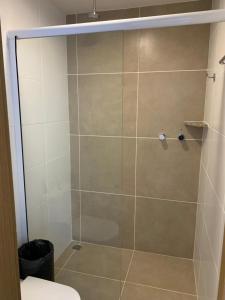 um chuveiro com uma porta de vidro na casa de banho em Ondas Praia Resort Apartamento em Porto Seguro