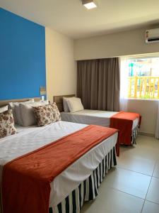 a hotel room with two beds and a window at Ondas Praia Resort Apartamento in Porto Seguro
