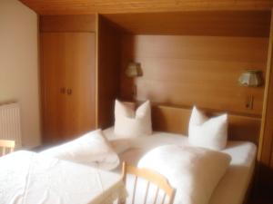 um quarto com uma cama com lençóis brancos e almofadas em Haus Alpenblick em Pertisau