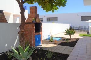 a backyard with a brick oven and a tree at Casa Tacande in Yaiza
