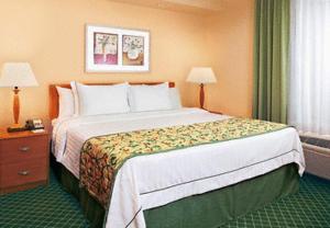 a hotel room with a large bed and two lamps at Baymont by Wyndham Kalamazoo East in Kalamazoo