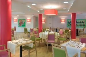 une salle à manger avec des tables, des chaises et des piliers rouges dans l'établissement DOMITYS Le Vallon des Bois, au Mans