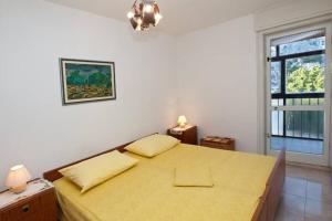 1 dormitorio con 1 cama con sábanas amarillas y ventana en Sara apartment Punta Omis near sandy beach, en Omiš