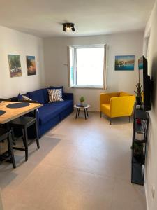 uma sala de estar com um sofá azul e uma cadeira amarela em Apartman Roko Duboka em Duboka