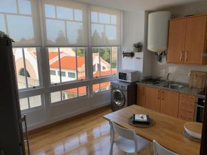 a kitchen with a table and some windows at Oktheway Praza do Conde in Puentedeume