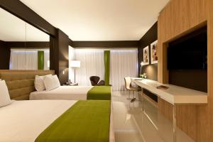 um quarto de hotel com duas camas e uma televisão em eSuites Savassi Toscanini em Belo Horizonte