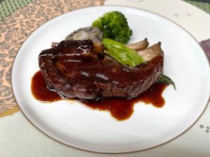 a plate of food with meat and broccoli on a table at Petit Hotel Kazekozou in Shinano