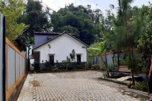 a white house with a fence and a brick driveway at Villa Dhanty in Bogor