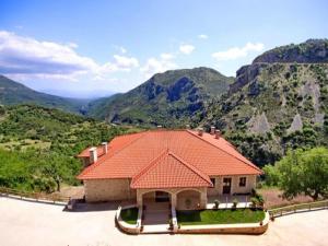 ein Haus mit einem orangenen Dach mit Bergen im Hintergrund in der Unterkunft Nerida Boutique Hotel in Dimitsana