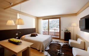 um quarto com uma cama, uma mesa e uma janela em Parkhotel Ladinia em San Vito di Cadore