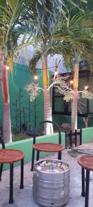 un patio con mesas, sillas y palmeras en Relax Home Aeropuerto-Tren Maya, en Chetumal