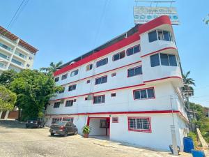 a white and red building with cars parked in front of it at Hotel Maria Bonita Acapulco in Acapulco