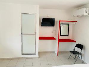 a room with a chair and a tv on a wall at Hotel Maria Bonita Acapulco in Acapulco
