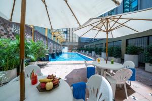 a hotel with a swimming pool and tables and umbrellas at Hotel Golden Dragon in Macau