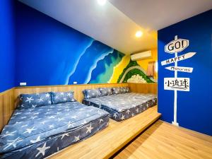 a room with two beds and a blue wall at Little Ryukyu Hermit Crab Homestay in Xiaoliuqiu