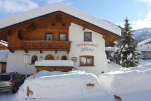 ペルティサウにあるAppartement Huberの雪の上に看板を載せた建物