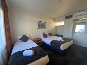 um quarto de hotel com duas camas e uma janela em The Astor Hotel Motel em Goulburn