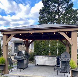 um gazebo de madeira com 2 comodidades para churrascos e um grelhador em Bramblebank Cottages em Harrison Hot Springs