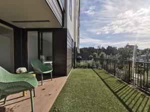 balkon z zielonymi krzesłami i trawą w budynku w obiekcie Brand New Lux 2 Bedroom Apartment w Auckland