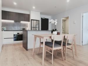 een keuken met een tafel en stoelen bij Brand New Lux 2 Bedroom Apartment in Auckland