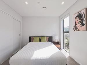 een witte slaapkamer met een groot bed en een raam bij Brand New Lux 2 Bedroom Apartment in Auckland