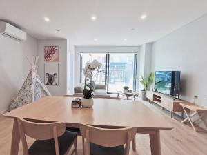 een woonkamer met een houten tafel en stoelen bij Brand New Lux 2 Bedroom Apartment in Auckland