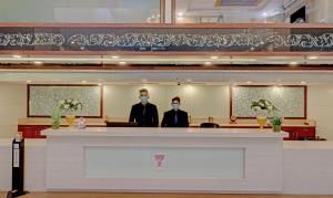 two people wearing face masks standing behind a counter at Treebo Tryst Pearl Avenue in Dehradun