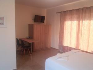 a bedroom with a bed and a desk and a window at Nereids Apartments-Erato in Petalidhion